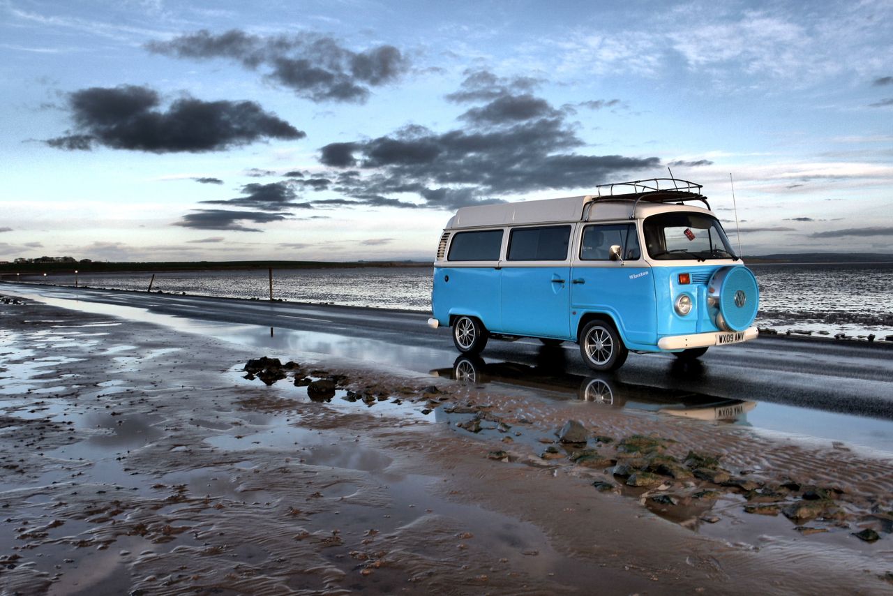 Campervan azul numa praia ao entardecer